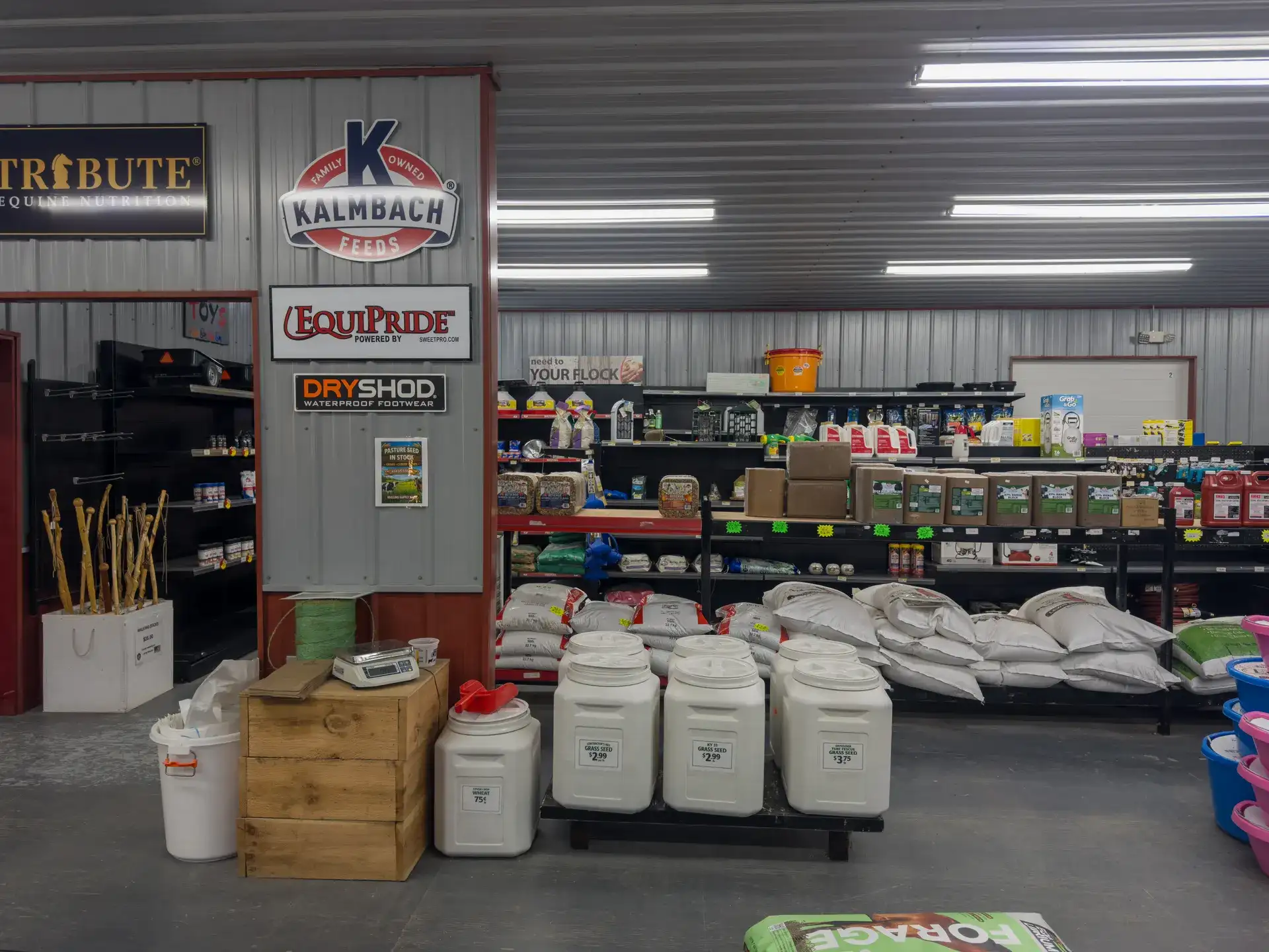 Feed and seed aisle at Mullins Supply Barn, with Kalmbach and Tribute signage and bulk seed bins